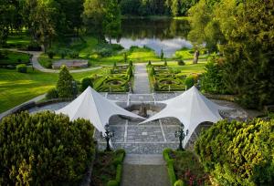 two white umbrellas in a garden with a pond at Hotel Bursztynowy Pałac in Koszalin