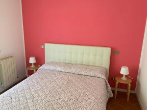 sypialnia z białym łóżkiem i czerwoną ścianą w obiekcie Albatros w Sirmione