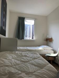 1 dormitorio con 2 camas y ventana en Appartement Waddengeluk Resort Amelander Kaap! en Hollum