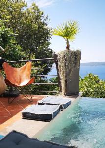 a pool with a chair and a palm tree on a patio at Art Gallery House in Crikvenica