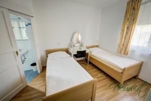 2 łóżka w pokoju z lustrem i umywalką w obiekcie Gasthof Neuwirt / Kressnig w mieście Klagenfurt