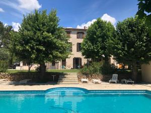 a house with a swimming pool in front of a building at LA BASTIDE DU GINESTE - Olives in Flayosc