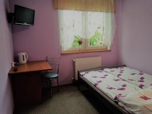 a bedroom with a bed and a desk and a window at Na Skwerku in Stronie Śląskie