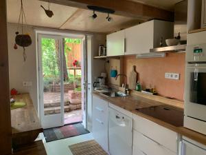a kitchen with white cabinets and a sliding glass door at Gîte Côté Verre in Meisenthal