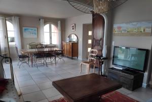 a living room with a tv and a dining room at Belle villa sur vaste plage Palavas Montpellier in Palavas-les-Flots
