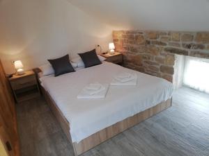 a bedroom with a large white bed with two plates on it at Apartmani Goga in Skradin
