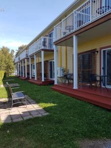 a row of houses with tables and benches on the lawn at Motel des Mariniers in Kamouraska