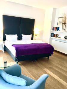 a bedroom with a bed with a purple blanket and a chair at Stein Boardinghouse in Koblenz