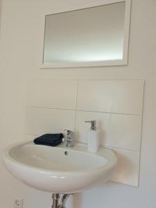 a white sink in a white bathroom with a mirror at HummelHaus 3 in Lindau in Lindau