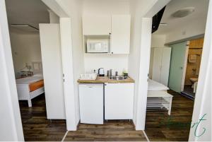 uma cozinha com um lavatório e um quarto com uma cama em Gasthof Neuwirt / Kressnig em Klagenfurt