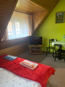 a bedroom with a bed with a red blanket and a table at Hotelik in Chełmno