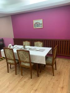 a table with chairs and a purple wall at Hotelik in Chełmno