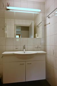 a white bathroom with a sink and a mirror at Casa Sper Gassa in Disentis