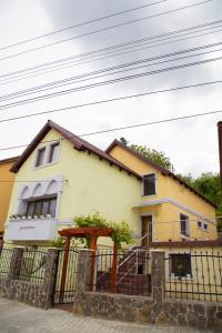een geel huis met een hek ervoor bij Cosbuc Residence & Villa in Sighişoara