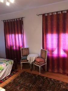 2 chaises et une table dans une chambre avec rideaux rouges dans l'établissement Milly Lake, à Claino