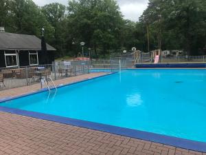 a large blue swimming pool with a playground at Wulft 47 Zonnig gezellig 6p chalet met zwembad in bosrijke omgeving op Familie Camping de Vossenburcht in IJhorst +41 photos