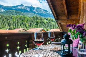 two glasses of wine sitting on a table on a balcony at Ferienwohnung Bergfrieden in Krün