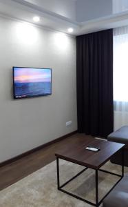 sala de estar con mesa y TV en la pared en Однокомнатная квартира по проспекту Коцюбинского, en Vínnytsia