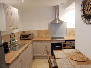a kitchen with white cabinets and a sink and a counter at Le soleil de Malaucène in Malaucène