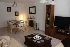 a living room with a television and a table with a dining room at Villa andaluza en zona Playa Barrosa con piscina y barbacoa in Chiclana de la Frontera