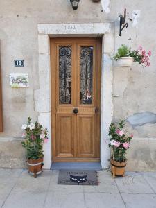 una puerta de madera en un edificio con dos macetas en Aux Portes Du Marais, en Ceyzérieu