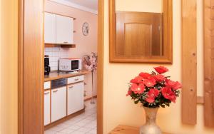 a kitchen with a vase with red flowers on a table at Ferienwohnung Cornelia in Bad Birnbach