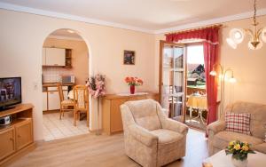 ein Wohnzimmer mit einem Sofa und einem Stuhl sowie eine Küche in der Unterkunft Ferienwohnung Cornelia in Bad Birnbach