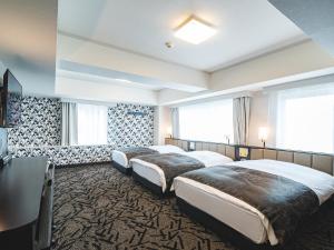 a hotel room with two beds and a table at APA Hotel Sapporo Susukino Eki Minami in Sapporo