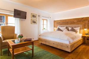 ein Schlafzimmer mit einem Bett, einem Stuhl und einem Tisch in der Unterkunft Seehotel Malerwinkel in Rottach-Egern