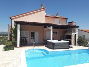 a villa with a swimming pool in front of a house at Villa Roza Murter in Murter