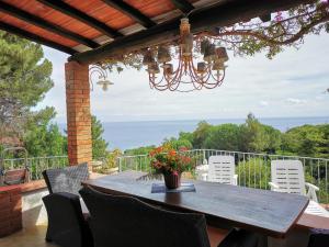a wooden table and chairs on a patio with a chandelier at casa panoramica bouganville in SantʼAndrea