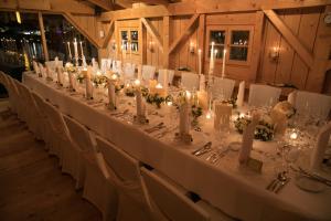 una mesa larga con sillas blancas y velas en Seehotel Malerwinkel, en Rottach-Egern