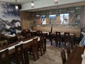 ein Restaurant mit Holztischen und -stühlen und Gemälden an der Wand in der Unterkunft Apartmán B 101 Vysoké Tatry in Starý Smokovec