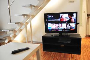 einen TV auf einem Stand in einem Wohnzimmer mit einer Treppe in der Unterkunft Ciro [Piazza Unità Italia] in Triest
