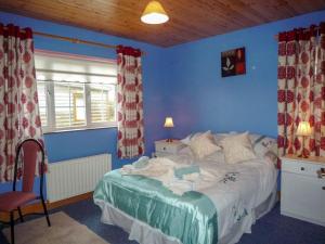 a bedroom with a bed with blue walls and a window at Ballyheigue Guesthouse in Heirhill