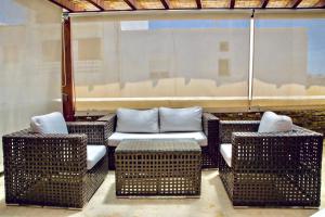 patio con sillas de mimbre, sofá y mesa en Renthousetinos 2, en Tinos