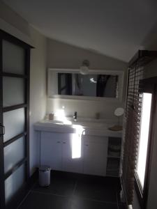 a bathroom with a white sink and a mirror at TERRASSE DES OCRES in Roussillon