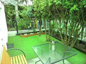 a garden with a glass table and chairs and trees at APARTAMENT BERMUDY in Świnoujście