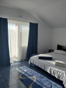 Vila Trandafirilor Costinești في كوستينيشت: غرفة نوم بسرير ونافذة ذات ستائر زرقاء