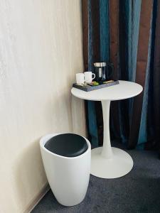 a white table and a white chair next to a table and a white bowl at Status Hotel in Poltava