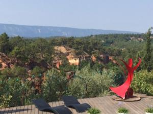 un aquilone rosso seduto in cima a un ponte di legno di TERRASSE DES OCRES a Roussillon