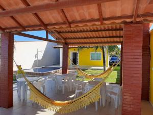 a hammock on a patio with a table and chairs at Casa à beira-mar, piscina in Pitimbu