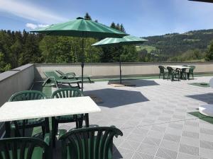 a patio with tables and chairs and an umbrella at Pension Jägerheim in Krumbach