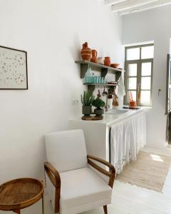 ein weißes Wohnzimmer mit einem Stuhl und einem Tisch in der Unterkunft Serifos Olive in Serifos Chora