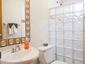 a bathroom with a white toilet and a sink at Casa Mulder in Puerto Morelos