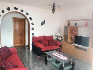 een woonkamer met een rode bank en een tafel bij Casa Rural Yeyo en el cráter del volcán in Tinguatón