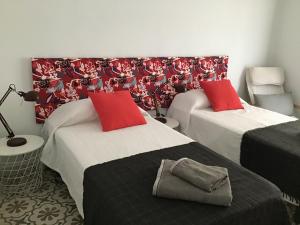 班約萊斯的住宿－El Llimoner，客房内的两张床和红色枕头