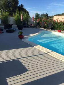 a swimming pool on a patio with chairs and flowers at Les Orangers in Aléria