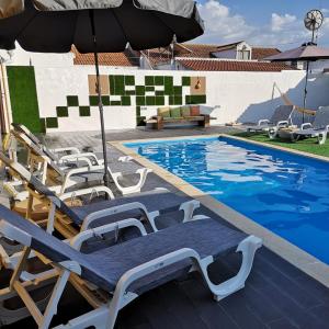 a swimming pool with lounge chairs and an umbrella at Casinhas do Canário in Montoito