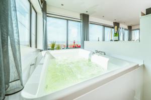 een witte badkamer met een bad en een groot raam bij Slapen in een Trechter in Harlingen
